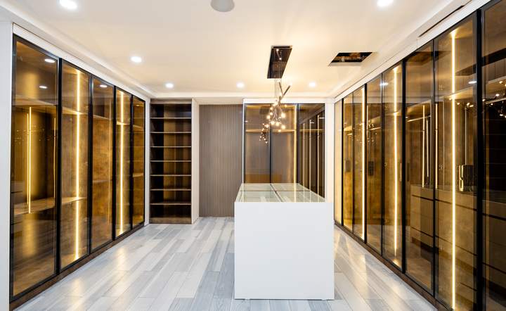 Walk-in dressing room with lit glass wardrobes